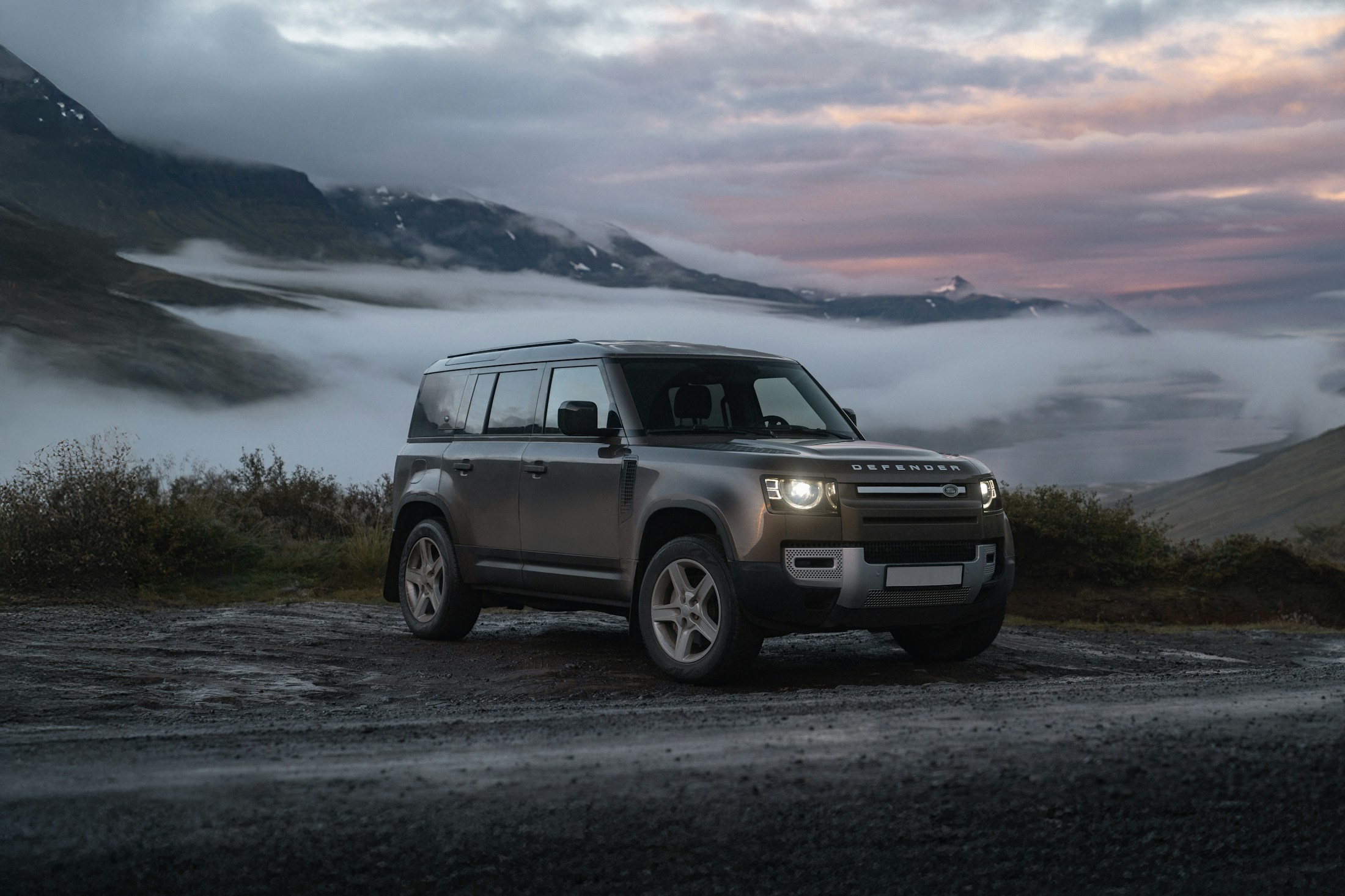 Land Rover Defender overlooking a mist-filled mountain valley